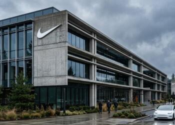Fachada de concreto y vidrio de un edificio de Nike con un gran logo de la marca.