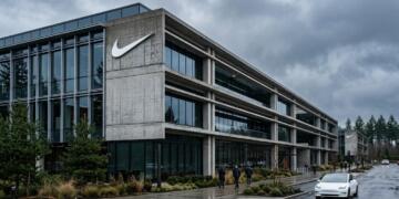 Fachada de concreto y vidrio de un edificio de Nike con un gran logo de la marca.