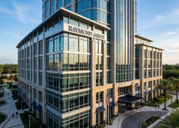 Edificio de Raymond James Financial con fachada de vidrio y piedra bajo la luz del sol matutino.