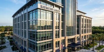 Edificio de Raymond James Financial con fachada de vidrio y piedra bajo la luz del sol matutino.