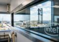 Ventana con logo grabado de Intel y vista exterior de un cohete Starship y un edificio de Tesla.