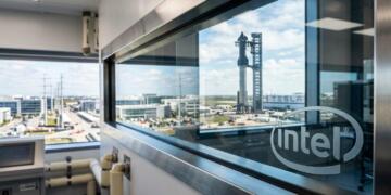 Ventana con logo grabado de Intel y vista exterior de un cohete Starship y un edificio de Tesla.