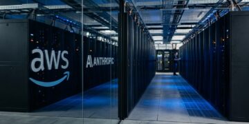 Pasillo de centro de datos moderno con logotipos de AWS y Anthropic en paneles de vidrio.