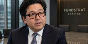 Tom Lee sentado de frente en escritorio en oficina institucional.