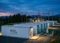 Unidades de batería de Duke Energy de 100MW en una subestación eléctrica con montañas al fondo.