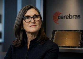 Cathie Wood junto a hardware de IA en entorno tecnológico sobrio.
