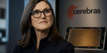 Cathie Wood junto a hardware de IA en entorno tecnológico sobrio.