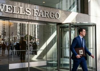 Hombre de traje azul lleva portafolios de Alcoa frente a edificio de Wells Fargo