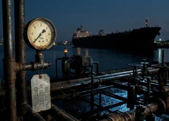 Manómetro en cero con etiqueta de 'DIESEL RESERVES: CRITICAL' y buque cisterna al fondo en cuba .