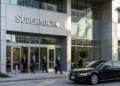 Entrada de Supermicro en San José con logo plateado, cristales modernos y paso de coche ejecutivo.