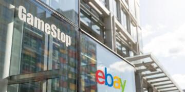 Vista de primer plano de los logotipos de GameStop y eBay en la fachada de vidrio de un edificio.