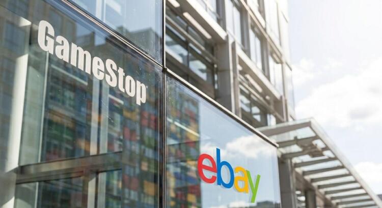 Vista de primer plano de los logotipos de GameStop y eBay en la fachada de vidrio de un edificio.