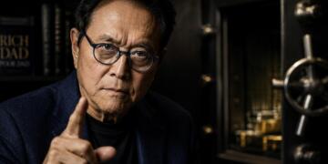 Robert Kiyosaki en retrato oscuro con gesto de advertencia firme.