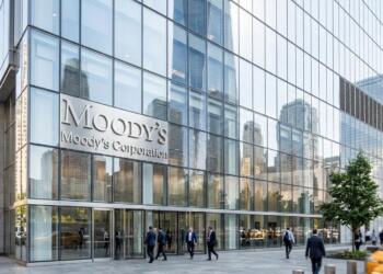 Vista de la fachada de vidrio del 7 World Trade Center con el logo de Moody's y peatones.