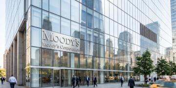 Vista de la fachada de vidrio del 7 World Trade Center con el logo de Moody's y peatones.
