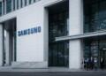 Entrada principal del edificio Samsung con personas caminando y proyecciones de datos en el vidrio.