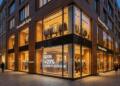 Fachada iluminada de tienda Zegna con pantalla digital que muestra crecimiento del 20%.