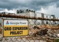 Cartel de Georgia Power en valla oxidada anunciando proyecto de red, sitio de construcción de fondo