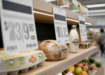 Etiquetas de precios dominan productos básicos en un supermercado.