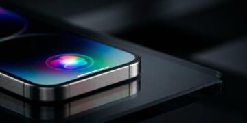 Primer plano de un smartphone de metal con el icono multicolor de Siri en su pantalla.