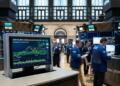 Pantalla con análisis bursátil de la NYSE frente a operadores en la bolsa.