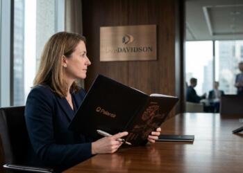Mujer en oficina corporativa frente al logo de D.A. Davidson sosteniendo una carpeta de Palantir.