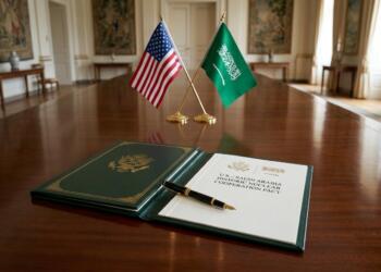 Documento oficial del pacto nuclear y banderas de EE. UU. y Arabia Saudita sobre una mesa.