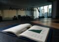 Un libro abierto con el informe de resultados de American Airlines y un bolígrafo en una mesa.