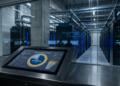 Pantalla táctil muestra distribución de inversión federal junto a servidores en un centro de datos.