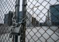 Valla metálica con cadena y candado bloqueando el acceso a una obra
