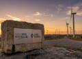 Paisaje al atardecer con aerogeneradores y placas solares en instalaciones de energía.