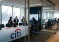 Profesionales en reunión de negocios dentro de la oficina de Citi con vista urbana.