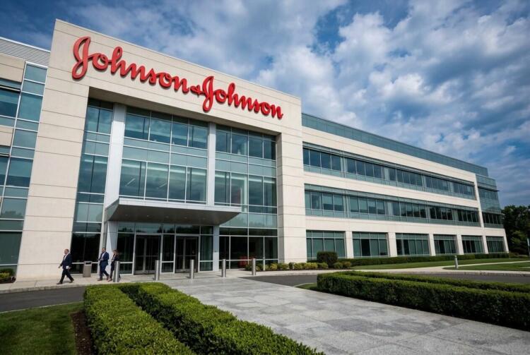 Vista exterior del edificio moderno de oficinas de Johnson & Johnson con empleados caminando cerca de la entrada.