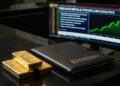 Tres barras de oro y un portafolio de Citadel Securities frente a una pantalla con gráficos.