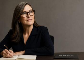 Cathie Wood junto al logo de AMD integrado en su escritorio de trabajo.