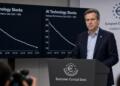 Hombre de traje habla en un atril del Banco Central Europeo frente a gráficos en pantallas.