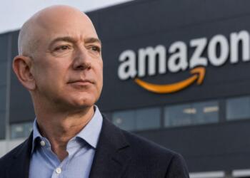 Jeff Bezos frente al logotipo de Amazon en sede corporativa.