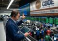 Operador de la CBOE con diadema sostiene una tablet con gráficos en la bolsa de opciones.