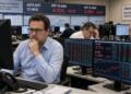 Operadores financieros revisan datos de bonos BTP y OAT en pantallas de una sala de control.