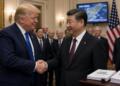 Donald Trump y Xi Jinping se estrechan las manos junto a banderas de EE. UU. y China.