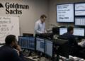 Analistas de Goldman Sachs trabajan en oficina con pizarras que muestran datos de la Fed.