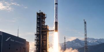 Cohete de Isar Aerospace despega junto a una torre de lanzamiento.