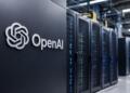 Logo de OpenAI frente a servidores de un centro de datos de IA modernos.