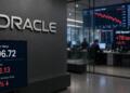 Pantallas con el valor intrínseco y el precio actual de las acciones de Oracle en oficina.