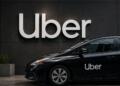 Vehículo de Uber frente a su logotipo en un entorno urbano moderno.