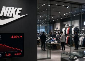 Pantalla frente a tienda Nike muestra gráficos bursátiles con caída del valor y precio.