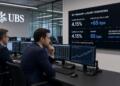 Operadores de UBS analizan datos de bonos del Tesoro frente a una gran pantalla con gráficos.