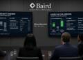 Directivos observan pantallas de Baird con análisis de ciberseguridad y energía.