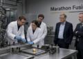 Bill Gates y científicos observan equipos en el laboratorio de Marathon Fusion.