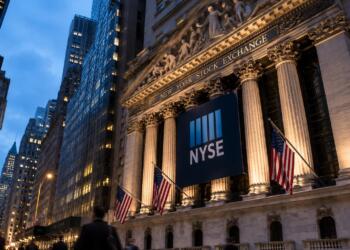 Fachada iluminada de la Bolsa de Nueva York al anochecer.